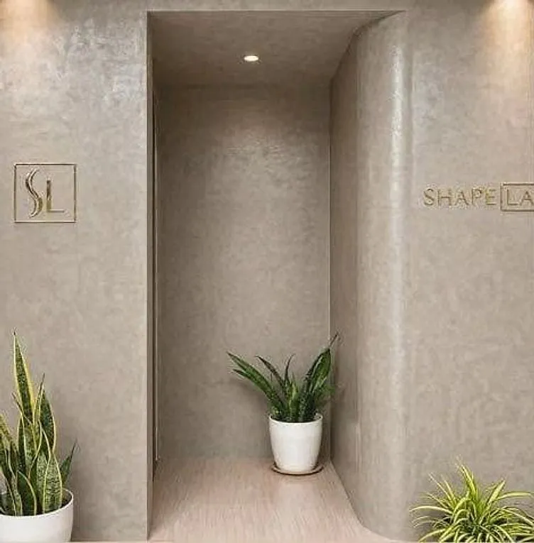 The curved entrance wall at ShapeLab with the gold SL monogram and ShapeLab lettering