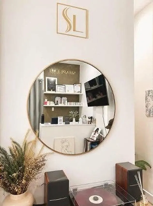 The mirror wall under the gold SL monogram at ShapeLab